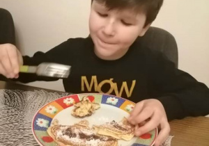 Chłopiec podczas degustacji swego deseru z talerza.